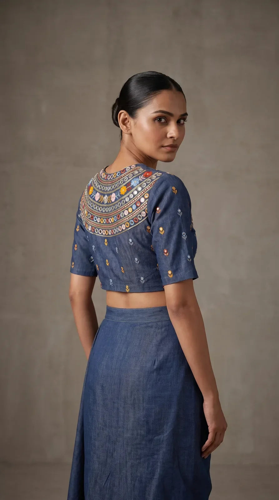 Back and sleeve detail of blue denim blouse with hand embroidery and mirror work